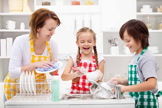 Kids and mother washing dishes - having fun together in the kitc