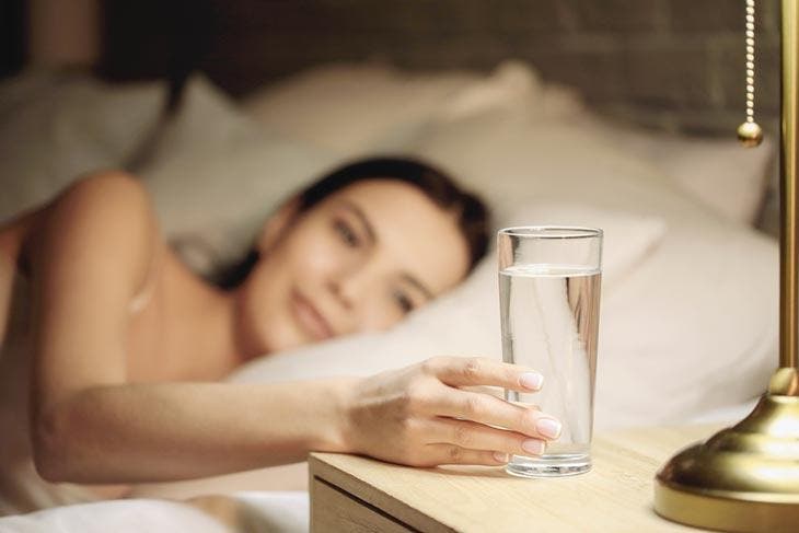 Boire un verre d’eau déposé sur la table de chevet