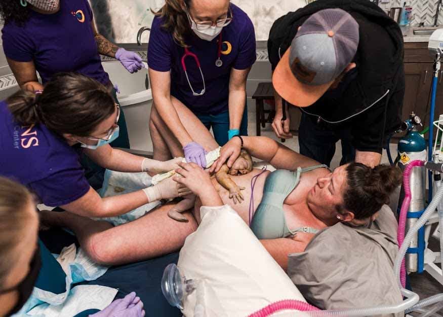 Femme qui vient d’accoucher entourée du personnel médical