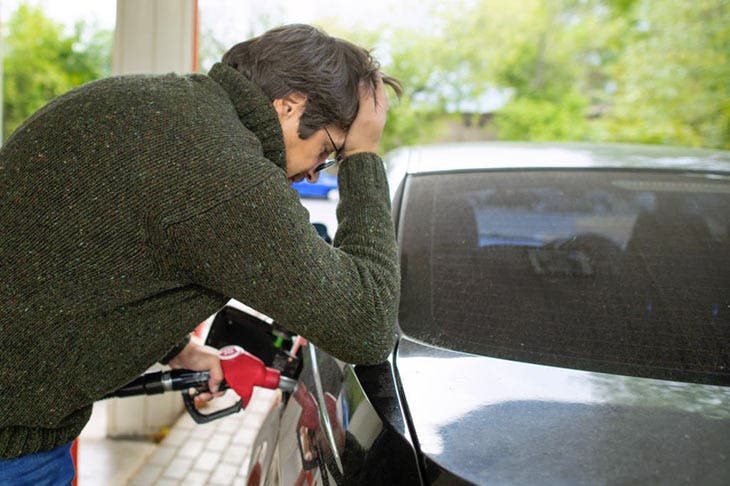 Homme dépité faisant le plein dans une station-service. source : spm