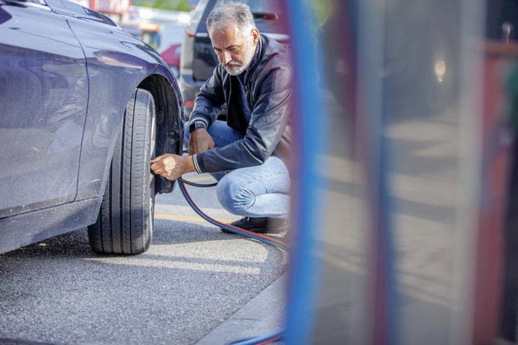 Homme gonflant les pneus de sa voiture