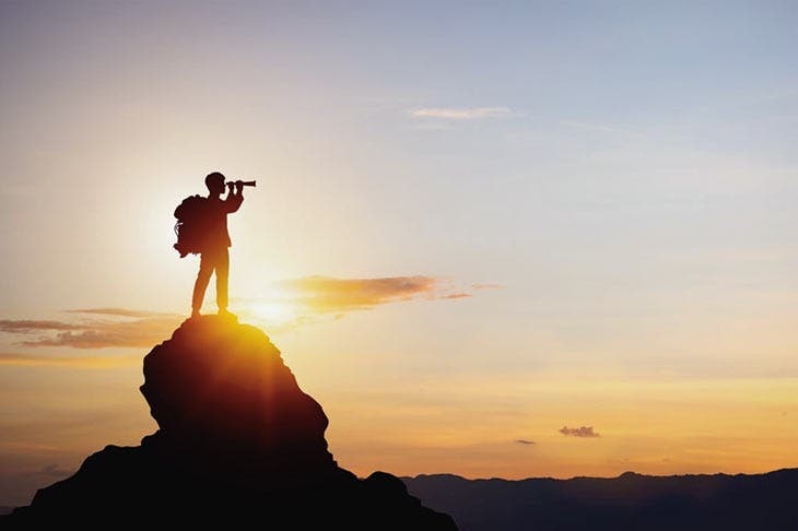 Homme se tenant au sommet d’une montagne par le crépuscule 