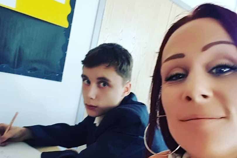 La maman est assise à côté de son fils en classe