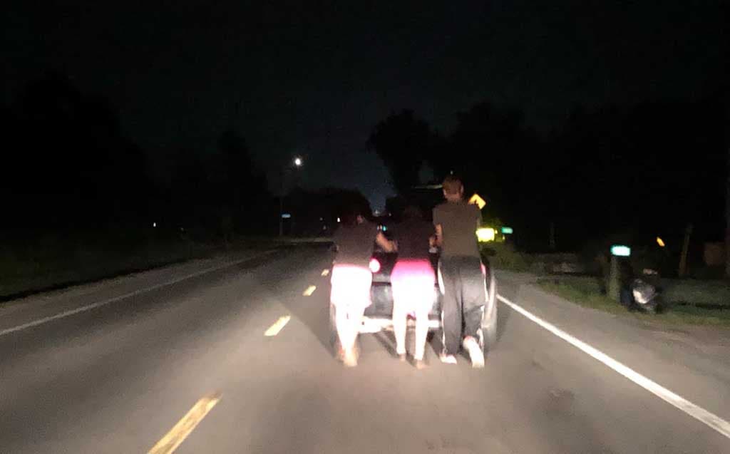 Les trois amis poussant à pieds la voiture tombée en panne