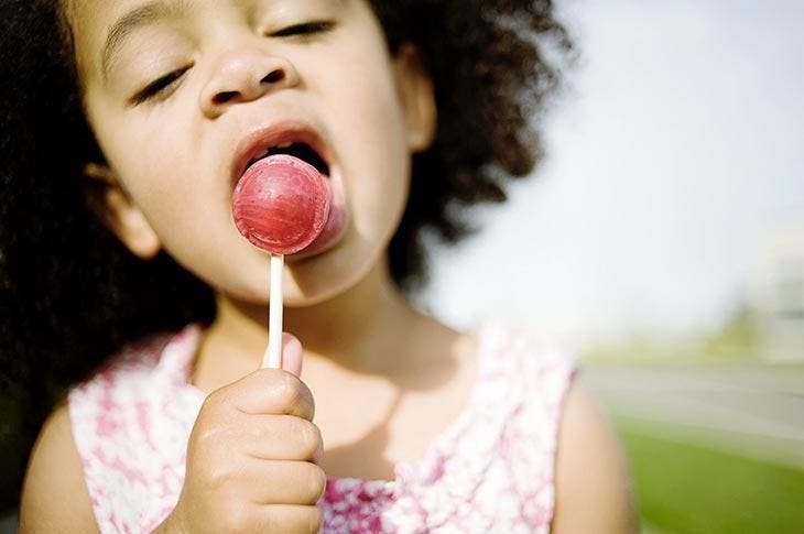 Une petite fille mange une sucette