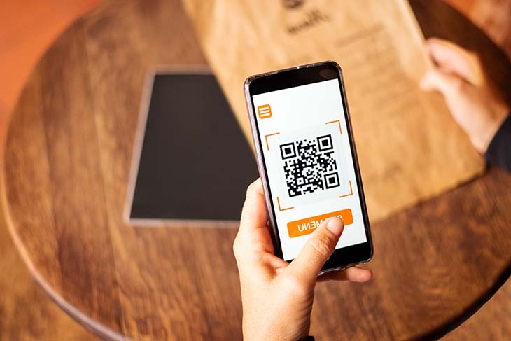 Une personne en train de scanner le menu numérique d’un café 